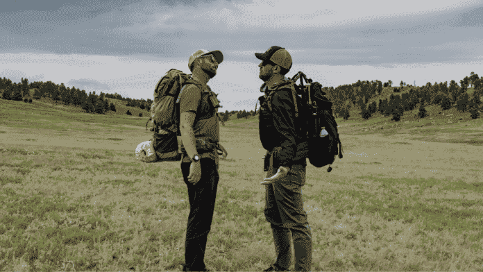 dan becker and eric hanson facing off in front of an open field while they compare their hiking and backpacking gear